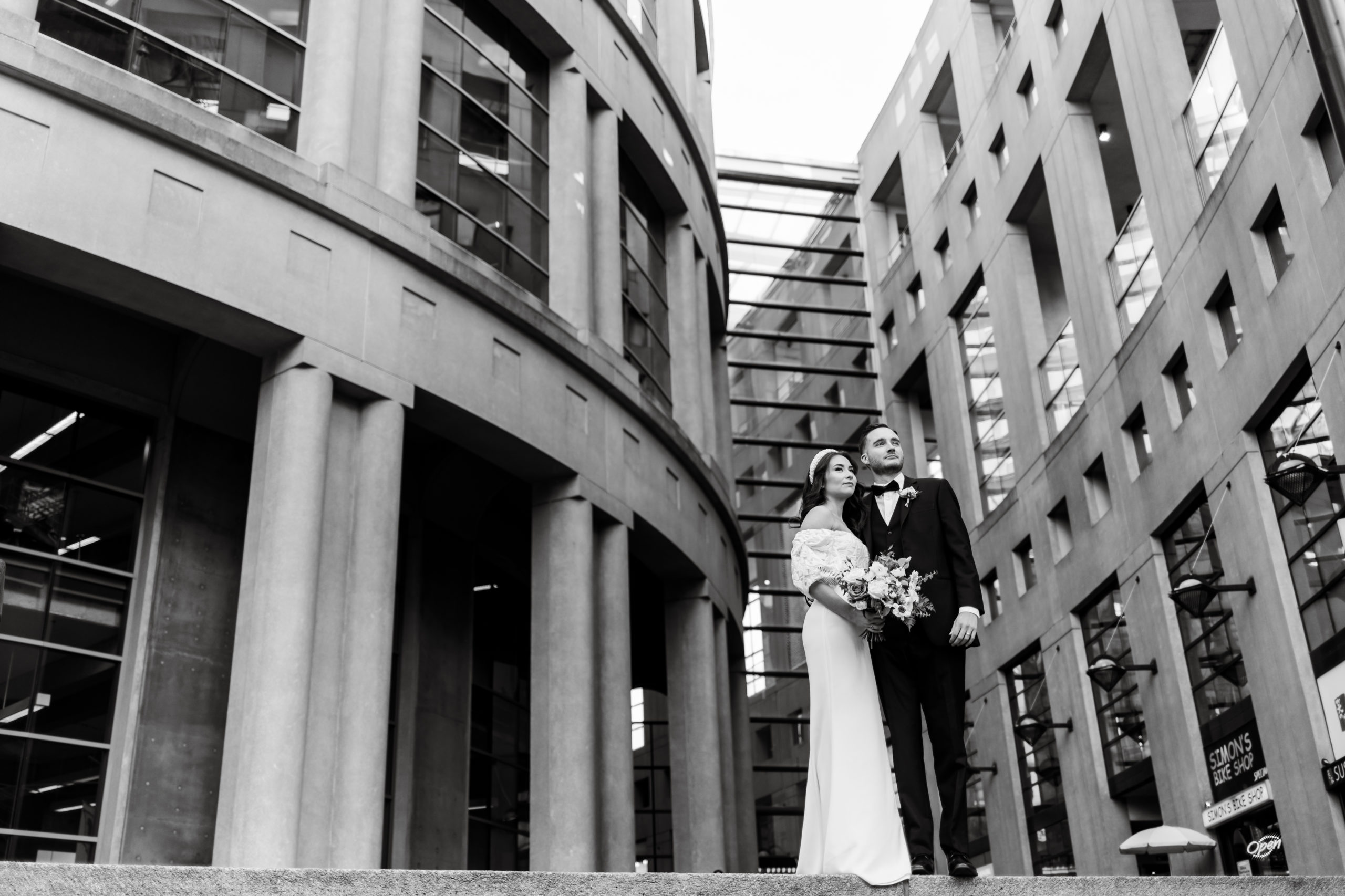 a bride and groom stand in front of the Vancouver public library