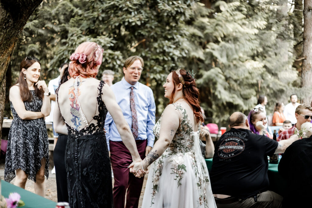 Brides chat with guests at their forest elopement in Langley