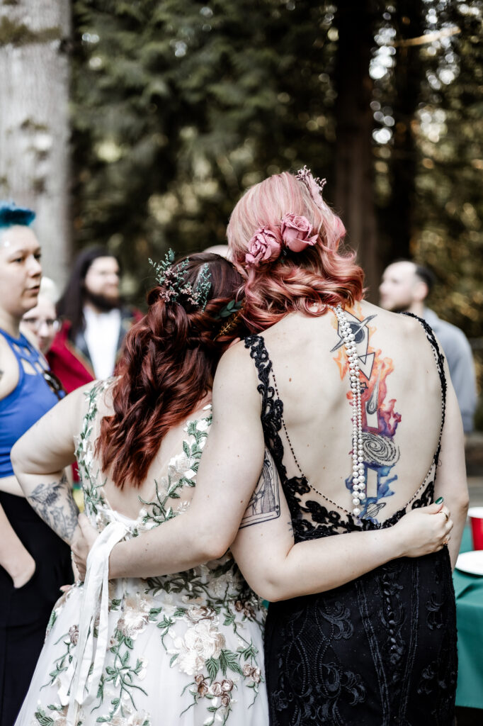 Brides put their arms each other at their forest elopement in Langley