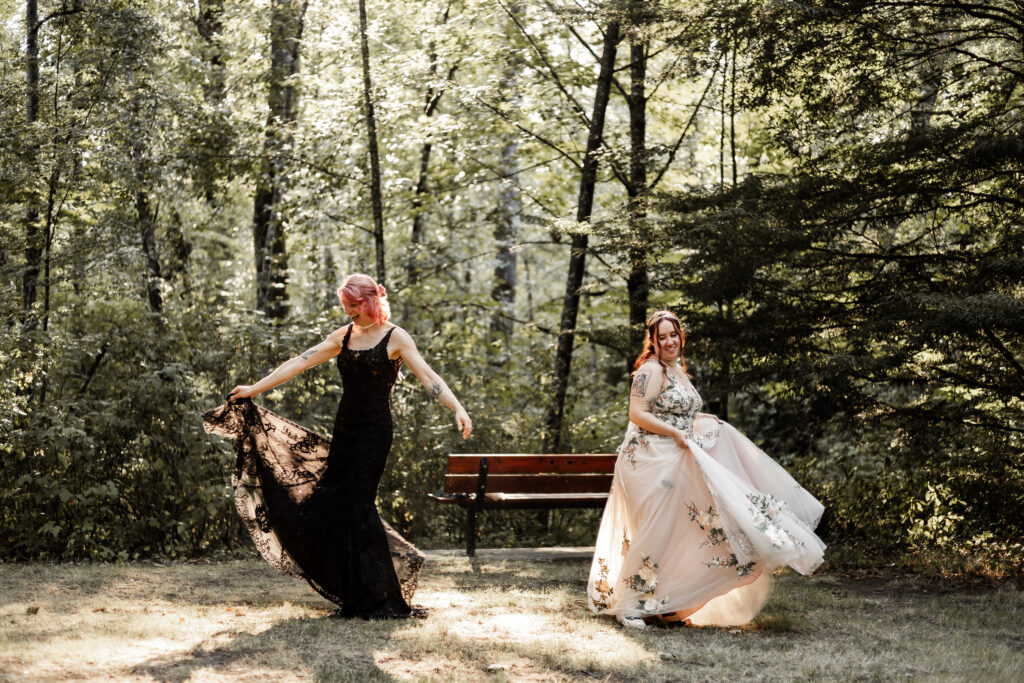 The brides both twirl in their dresses at their forest elopement in Langley