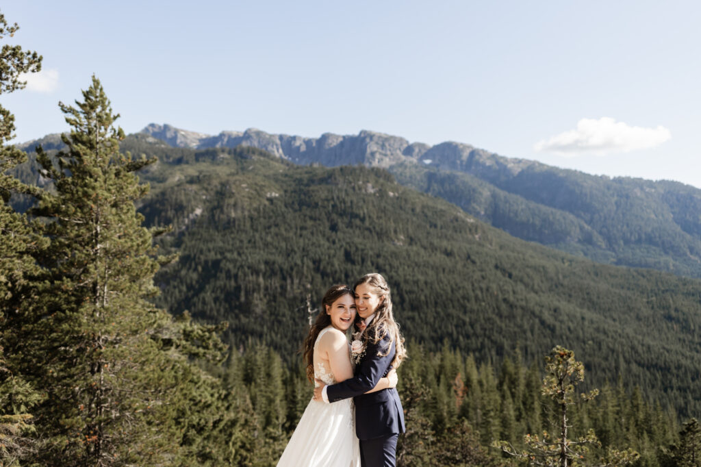 The couple embrace in front of the big mountains at this Sea to Sky Gondola wedding