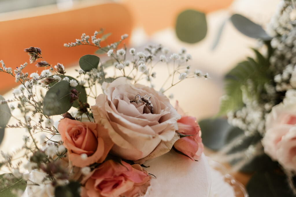 An up close of wedding rings on top of the flower cake topper at this Sea to Sky Gondola wedding