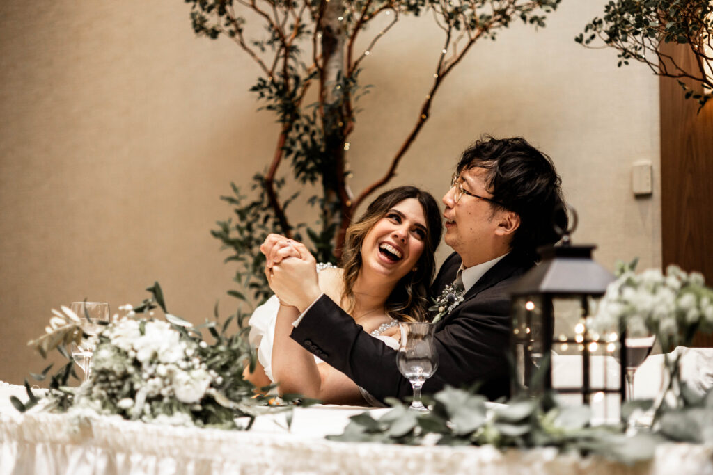 The bride and groom laugh together during speeches at their downtown Vancouver Marriott Pinnacle wedding