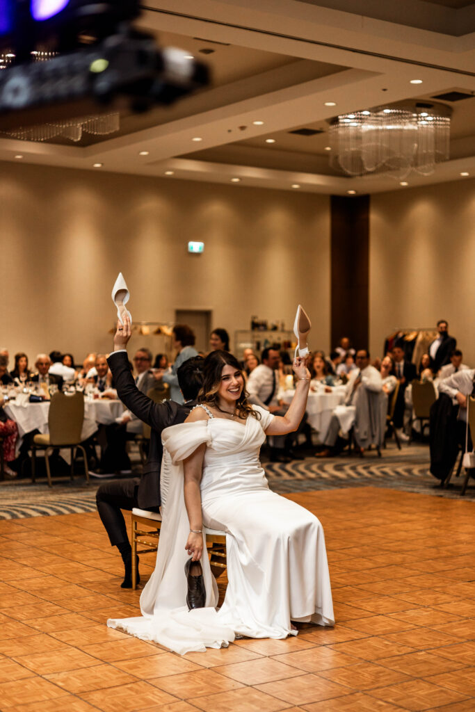 The bride and groom hold up their shoes during the shoe game at their downtown Vancouver Marriott Pinnacle wedding