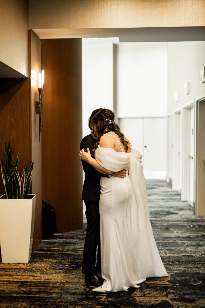 The bride and groom share a hug in front of the elevators at this downtown Vancouver Marriott Pinnacle wedding