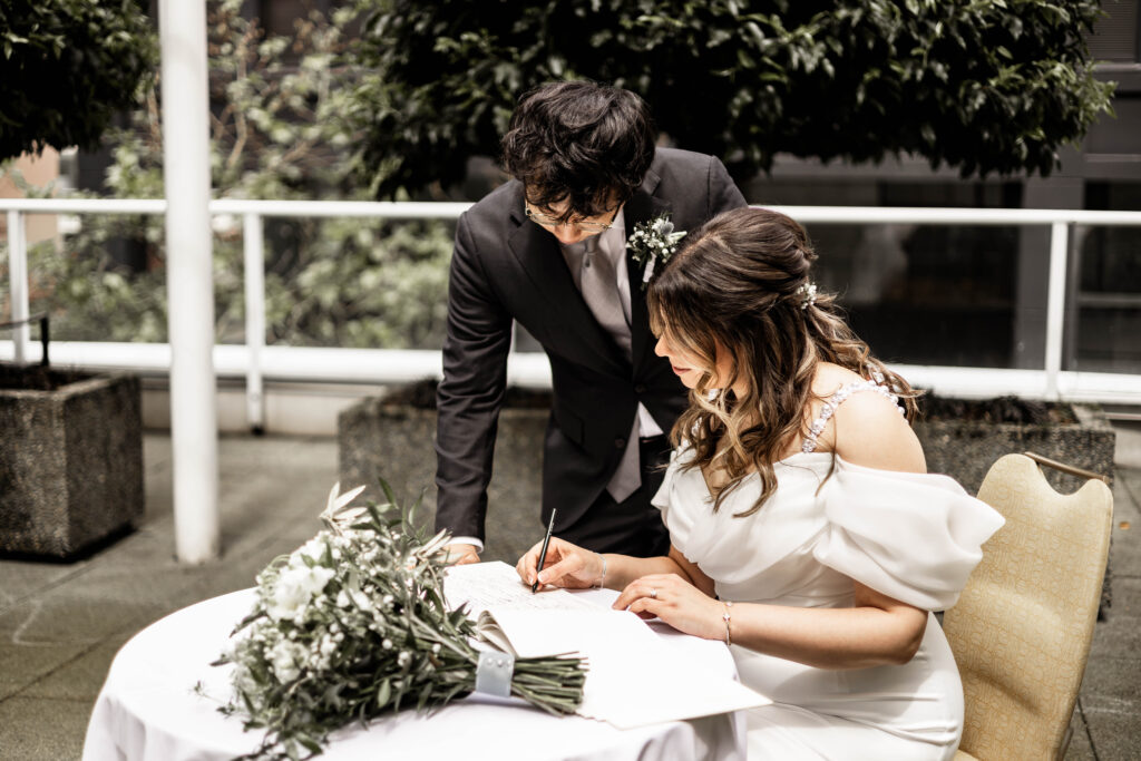 The bride and groom sign their marriage papers at this downtown Vancouver Marriott Pinnacle wedding