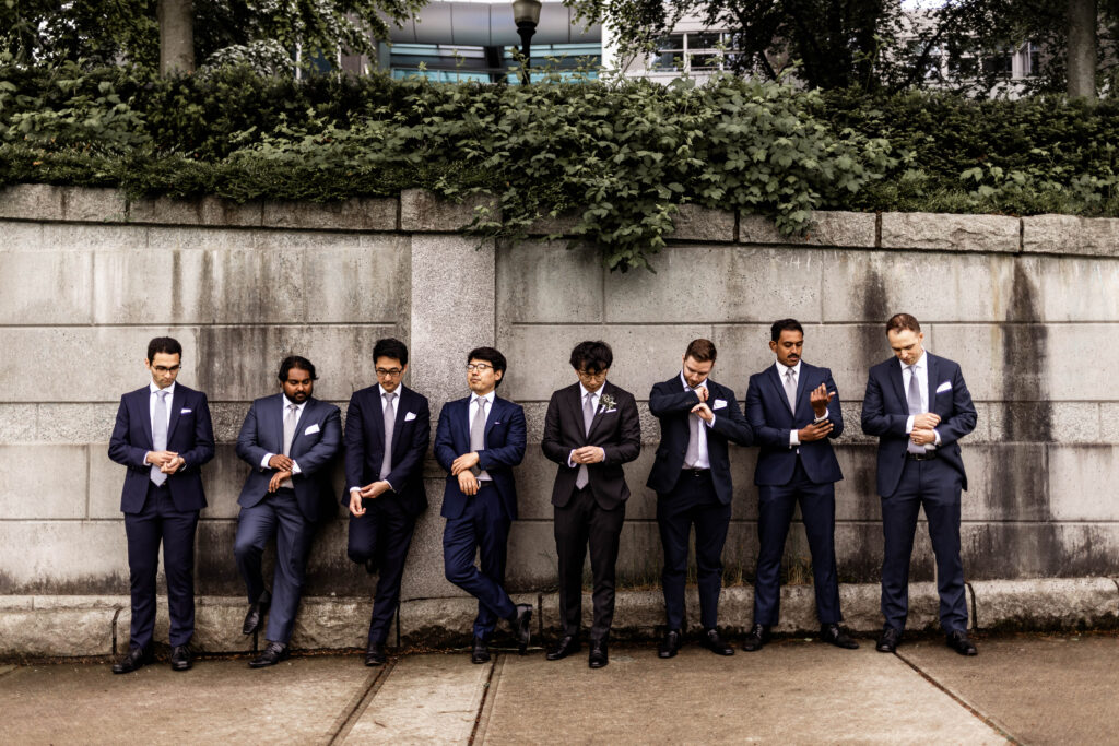 Groomsmen adjust their cuff links at the seawall water walk at this downtown Vancouver Marriott Pinnacle wedding