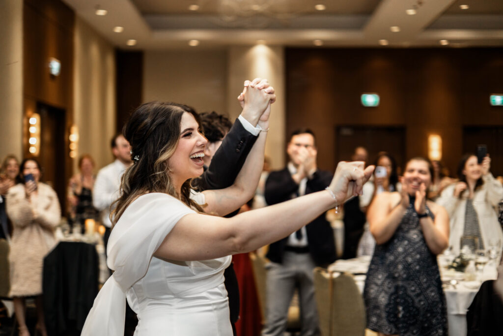 The bride and groom hold hands as they enter their reception at their downtown Vancouver Marriott Pinnacle wedding