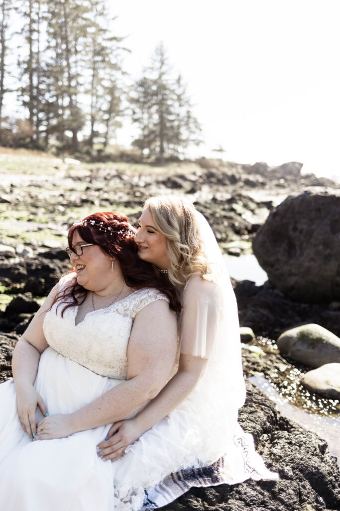 The brides snuggle together on the beach at their Black Rock Oceanfront Resort wedding.