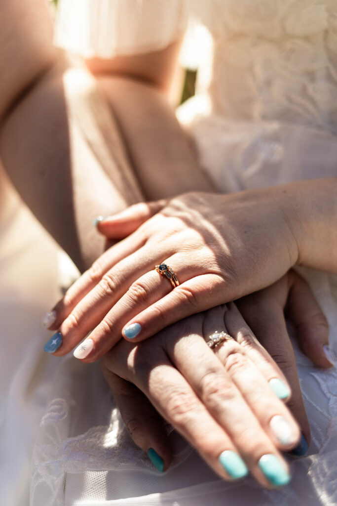 An upclose of the brides new wedding rings. Their hands are stacked on top of each other, showing off their rings.