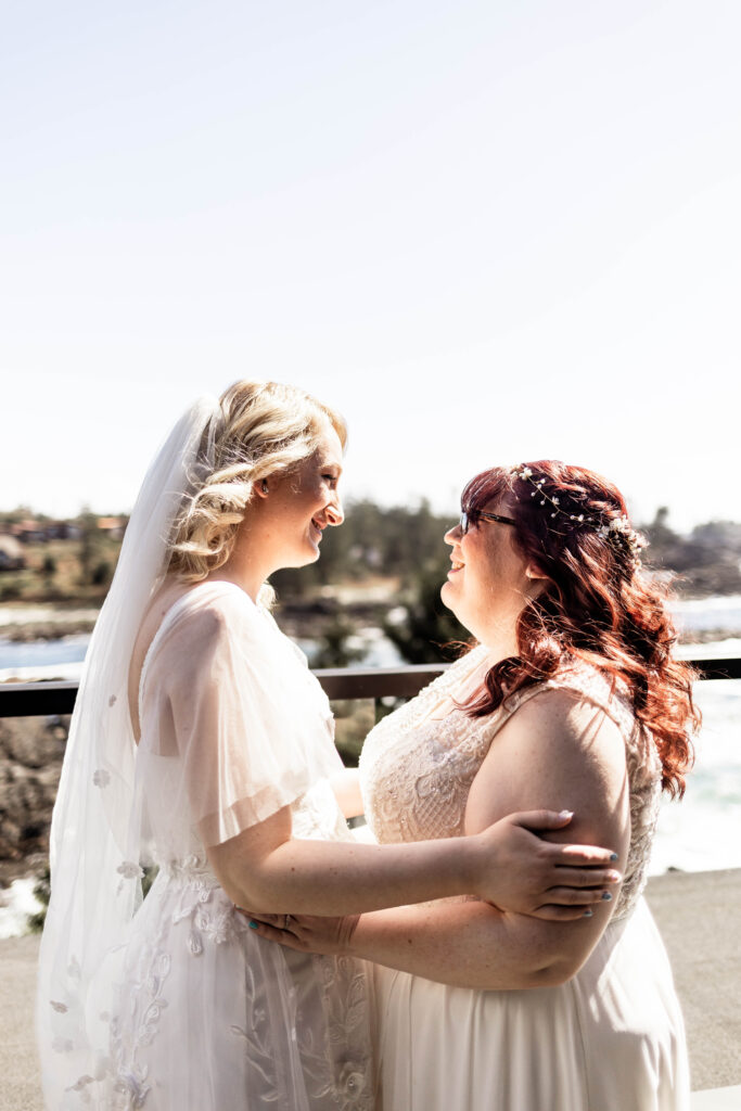 Two brides admire each other in their wedding attire at their Black Rock Oceanfront Resort wedding.