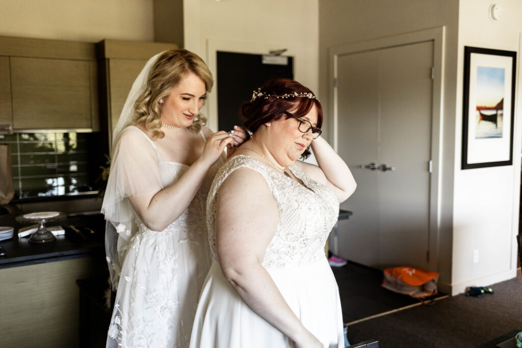 A LGBTQ couple helps each other get dressed for their Black Rock Oceanfront Resort Wedding