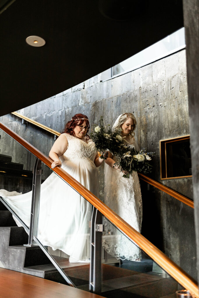 An LGBTQ couple walk down the stairs of Black Rock Oceanfront Resort's wine cellar to their ceremony.