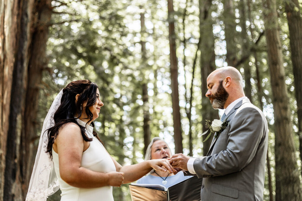 A couple exchange rings as a sign for the commitment to one another during their redwood forest elopement.