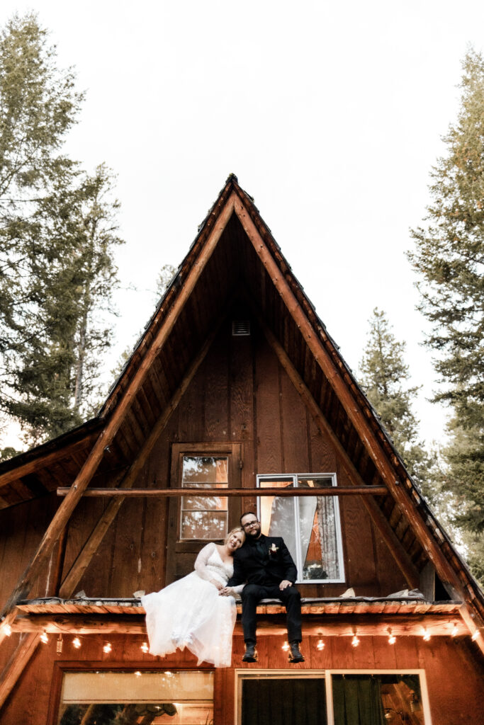 bride and groom pose on the balcony of the A-frame cabin at this cabin elopement