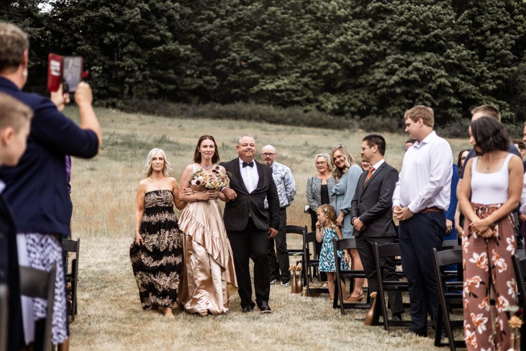 Bride is walked down the aisle by her parents at this Church and State Winery wedding