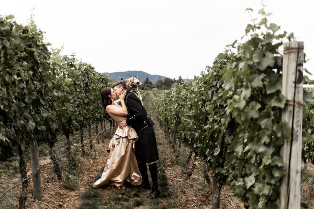 Bride and groom kiss between the rows of the vineyard at this Church and State Winery wedding