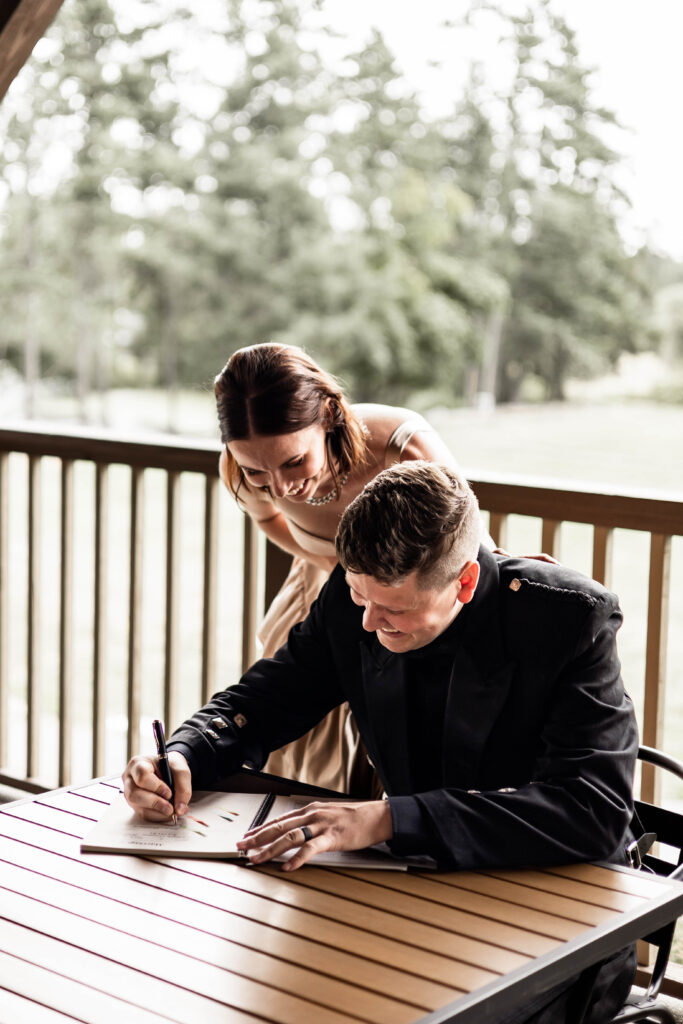 The newly weds laugh as the groom signs the marriage papers at this Church and State Winery wedding