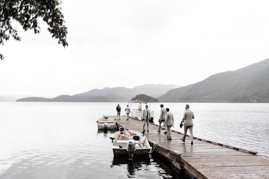 The groomsmen walk on the dock towards a boat at their canim lake wedding