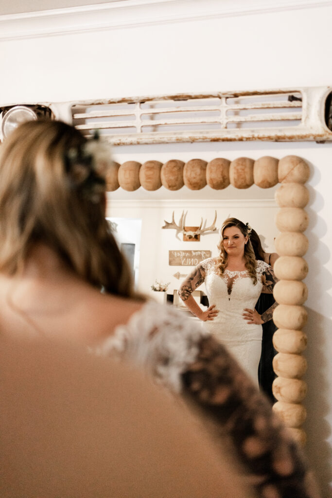 The bride admires herself in her wedding dress at this canim lake wedding
