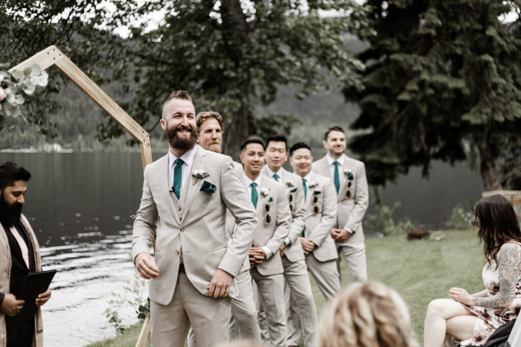 The groom smiles as his bride walks down the aisle at this canim lake wedding