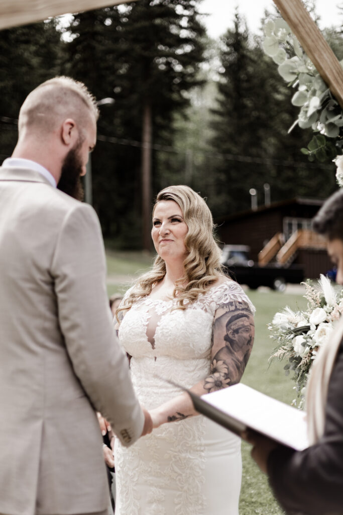 The bride smiles at her groom at the altar at this canim lake wedding