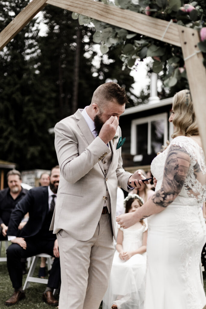 The groom wipes away a tear during the ceremony at this canim lake wedding