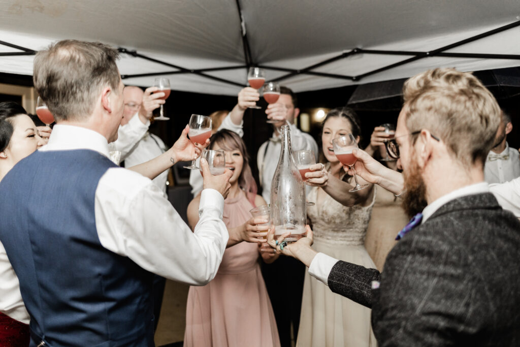 The bridal party raises their glasses in a cheers at this Gibsons Island summer camp wedding at Camp Elphinstone