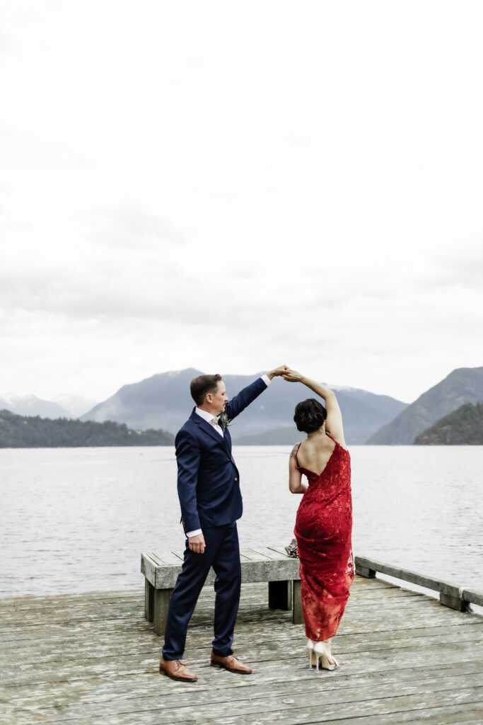 The groom twirls his bride in front of the view at their Gibsons Island summer camp wedding at Camp Elphinstone