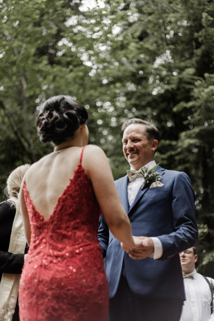 The groom smiles at his bride as they stand at the altar at this Gibsons Island summer camp wedding at Camp Elphinstone