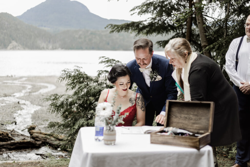 The bride and groom sign their marriage papers at their Gibsons Island summer camp wedding at Camp Elphinstone