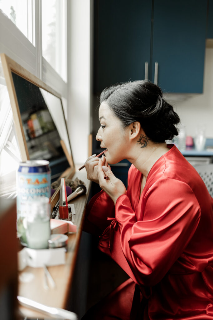 The bride gets ready by putting lipstick on at this Gibsons Island summer camp wedding at Camp Elphinstone