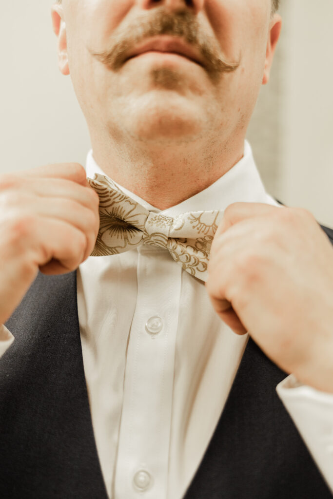 The groom adjusts his bowtie at this Gibsons Island summer camp wedding at Camp Elphinstone