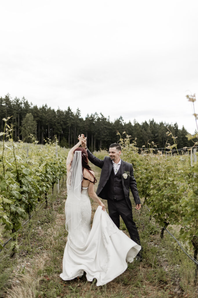 groom twirls bride in the vineyard at this Cobble Hill Winery wedding