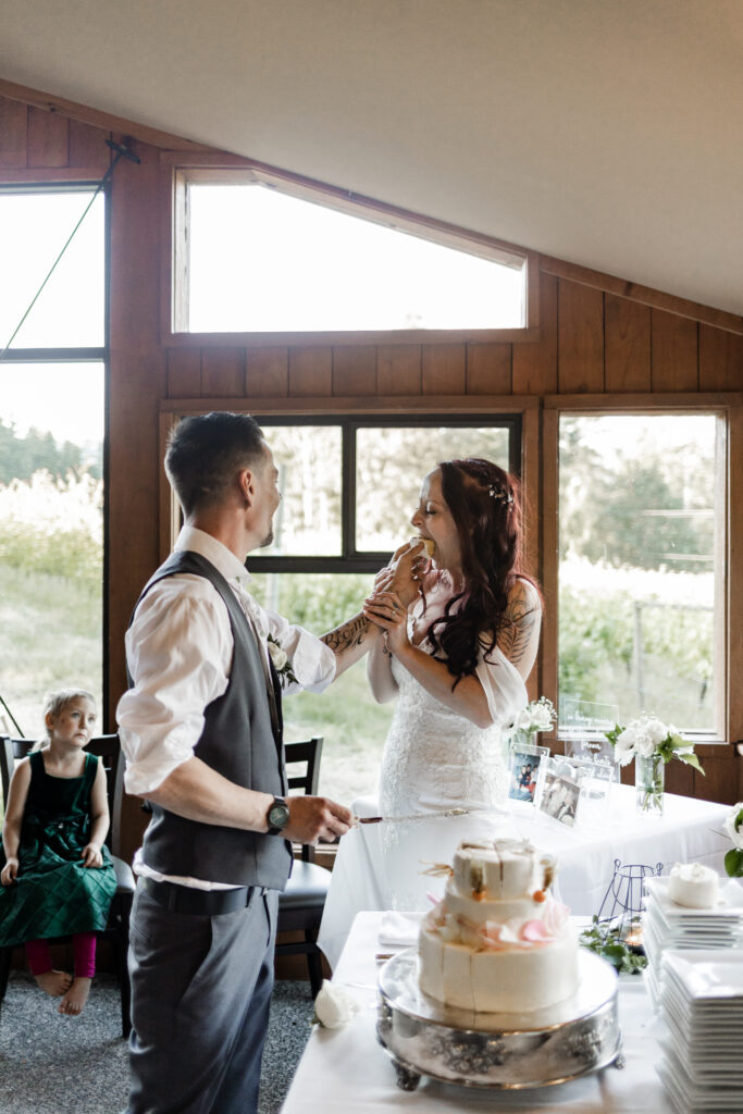 bride and groom feed each other cake at this Cobble Hill Winery wedding