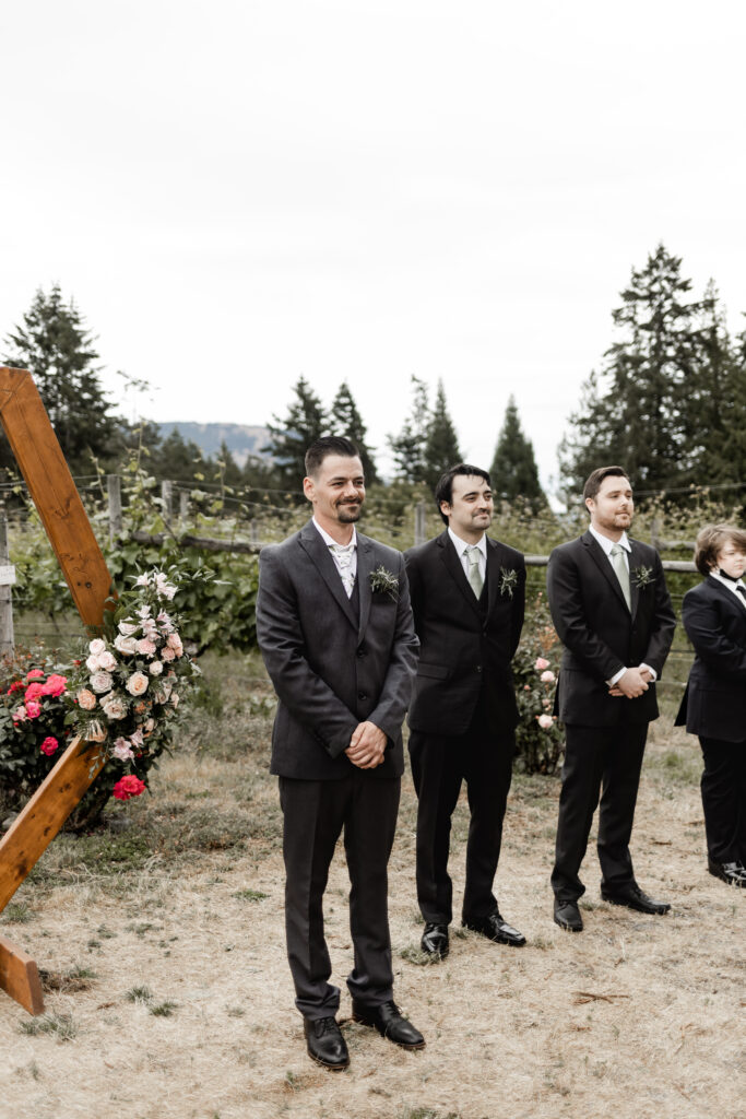 groom waits for his bride at the end of the aisle at this Cobble Hill Winery wedding