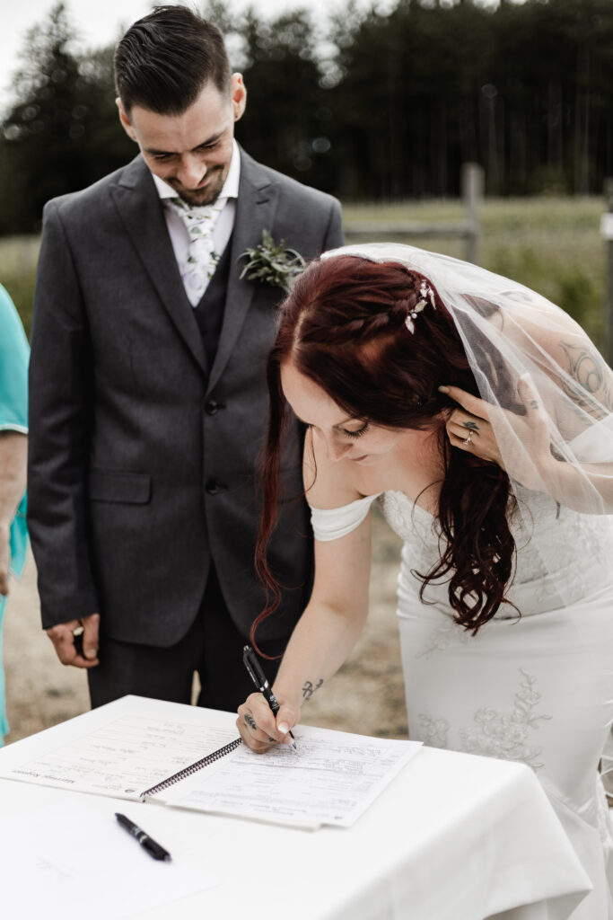 bride signs wedding papers at this Cobble Hill Winery wedding