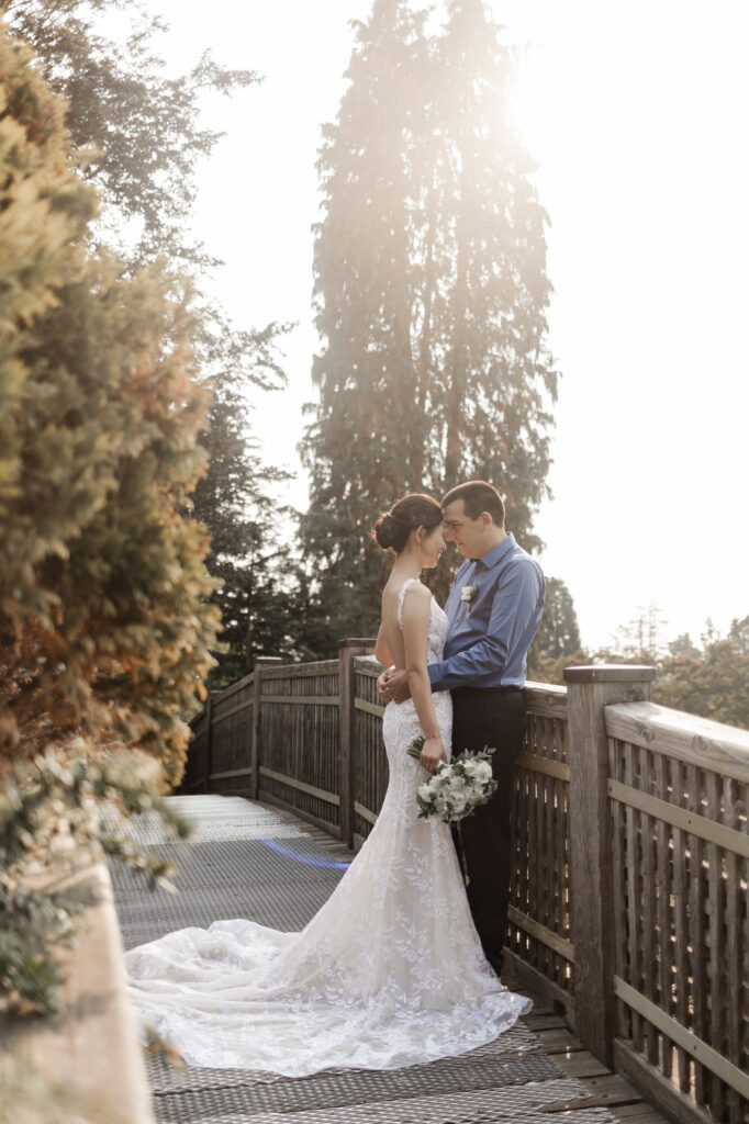 The couple touch noses on the wooden bridge at this Bloedel Conservatory wedding 