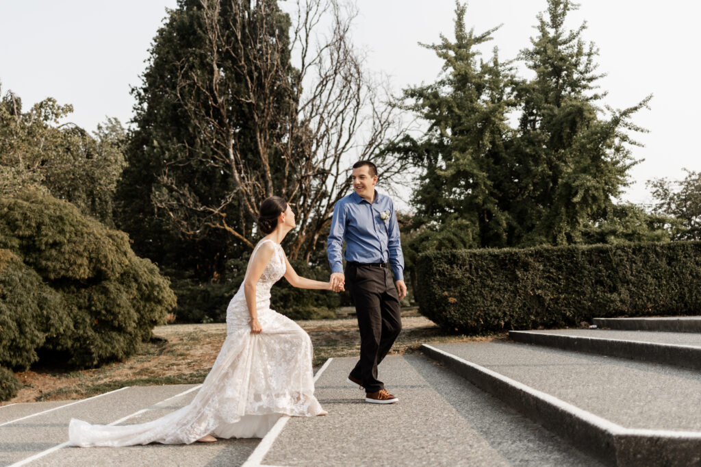 The couple walk up large steps outside the conservatory at this Bloedel Conservatory wedding 