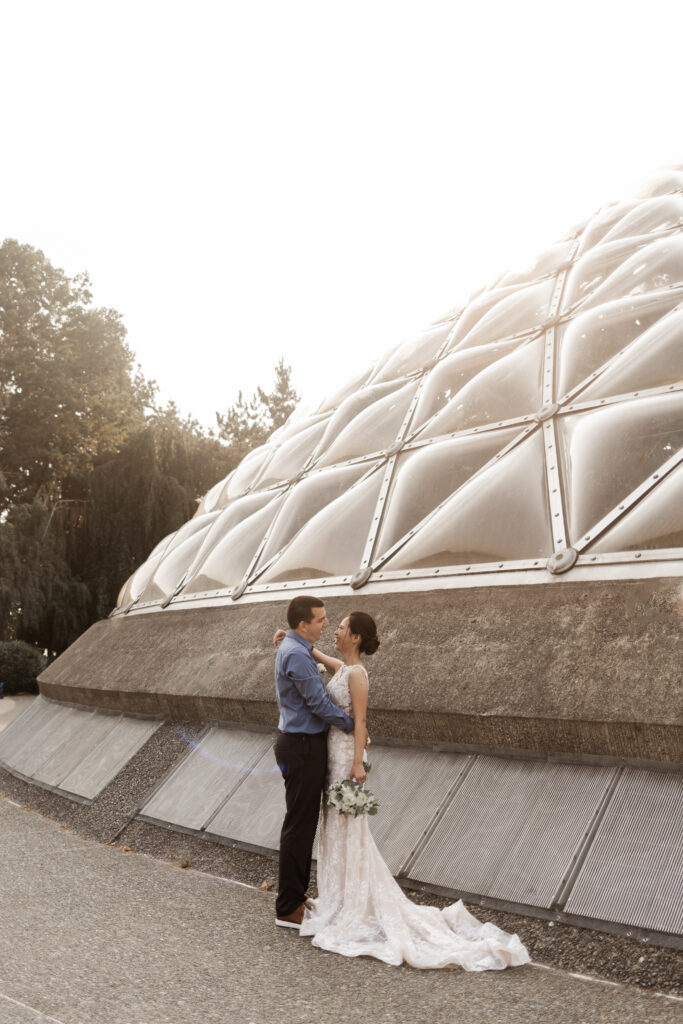 The couple pose in front of the conservatory at this Bloedel Conservatory wedding 