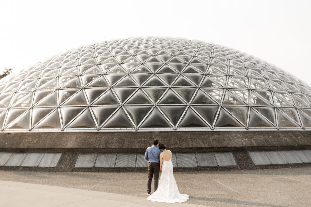 The bride and groom looking at the large dome at this Bloedel Conservatory wedding 