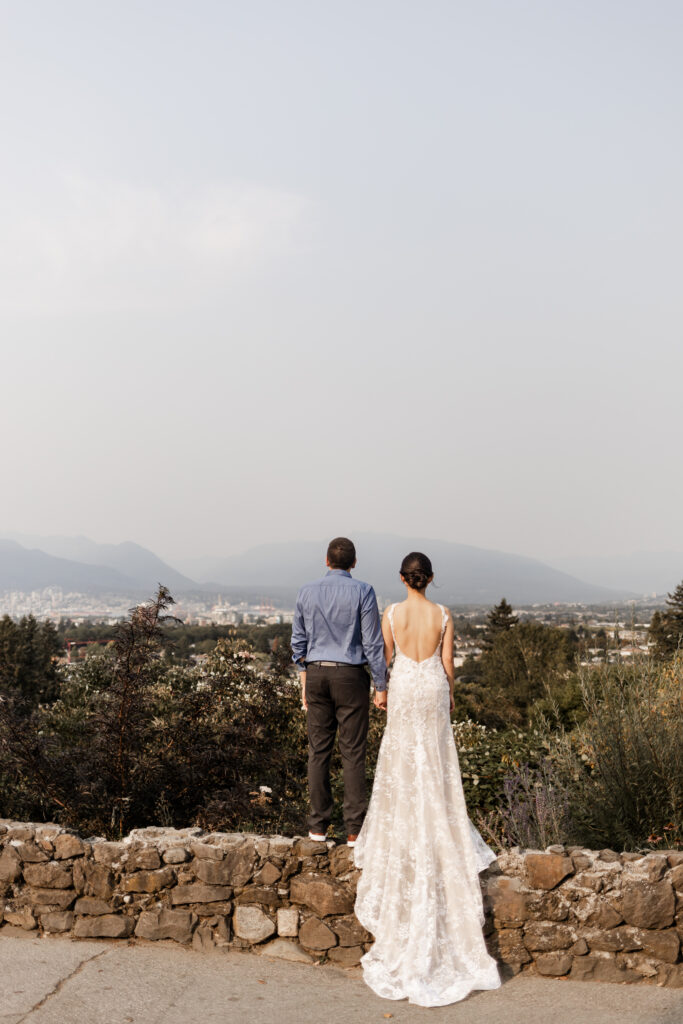 The couple stand on a small wall looking over the view of Vancouver at this Bloedel Conservatory wedding 