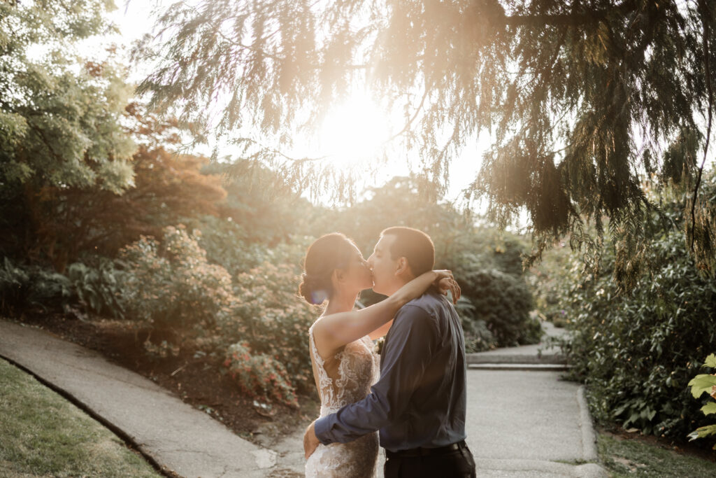 The couple share a kiss as the sun streams in from behind at this Bloedel Conservatory wedding 