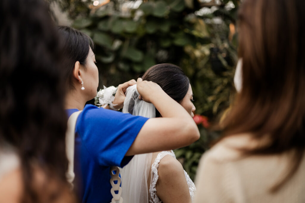 The brides friend puts veil in the brides hair at this Bloedel Conservatory wedding 