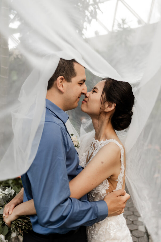 The bride and groom pose underneath the veil at this Bloedel Conservatory wedding 