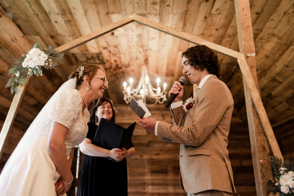 The bride laughs as the groom says his vows during the ceremony at this Estate 248 wedding in Langley, British Columbia