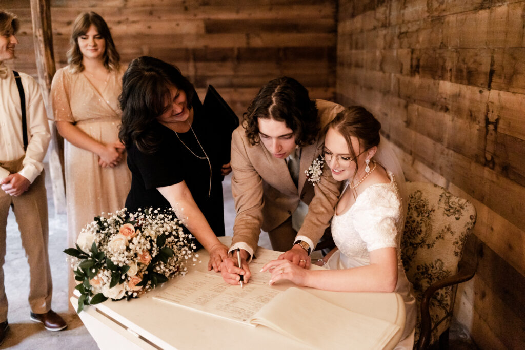 The officiant directs the bride and groom where to sign on their marriage papers at this Estate 248 wedding in Langley, British Columbia