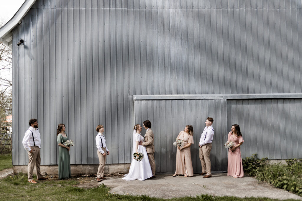 Bridal party poses in front of blue barn at this Estate 248 wedding in Langley, British Columbia