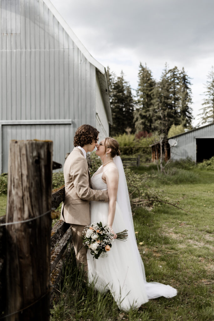 Bride and groom pose nose to nose in front of the blue barn at their Estate 248 wedding in Langley, British Columbia