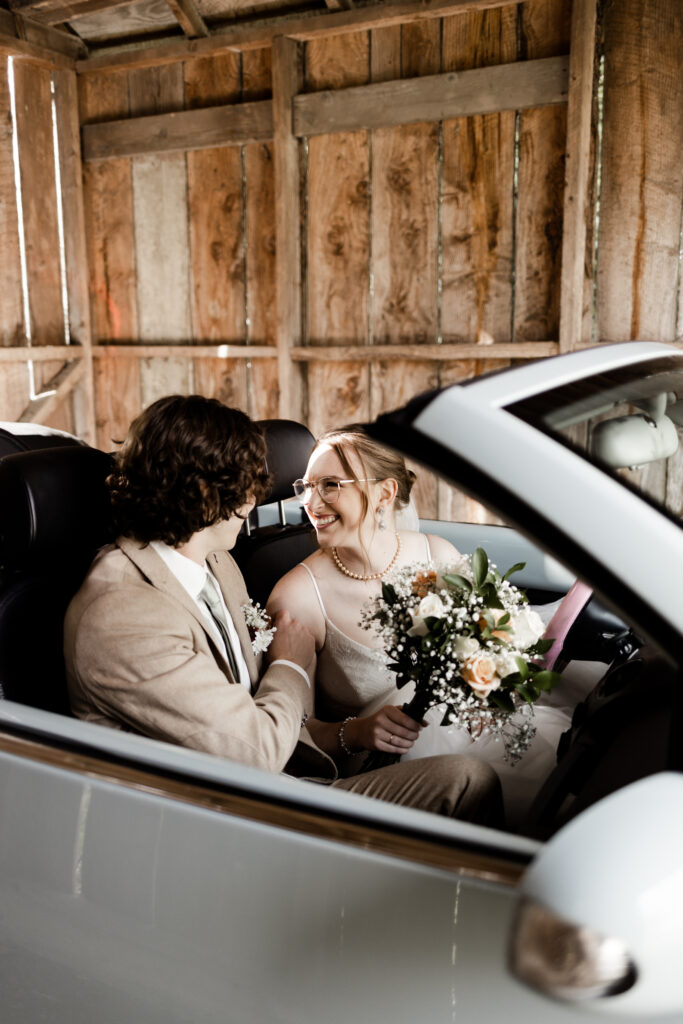 The bride and groom smile at each other from the inside of a baby blue Volkswagon at their Estate 248 wedding in Langley, British Columbia